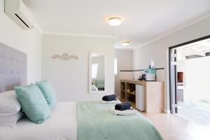 a white room with a bed with blue pillows at 401 Rozendal Cottages in Stellenbosch