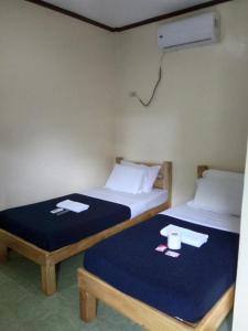 2 letti in una camera con lenzuola blu e cuscini bianchi di Alona KatChaJo Inn a Panglao