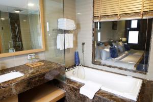 Ciao SaiGon Hotel & Spa في مدينة هوشي منه: حمام مع حوض ومرآة كبيرة
