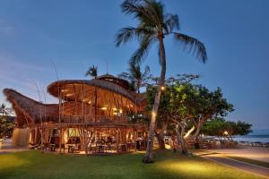 ein Gebäude mit einem Strohdach und einer Palme in der Unterkunft Nusa Dua Beach Hotel & Spa, Bali in Nusa Dua