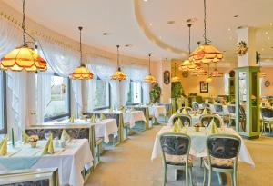 a restaurant with white tables and chairs and windows at Landgasthof & Hotel Waldow in Guben