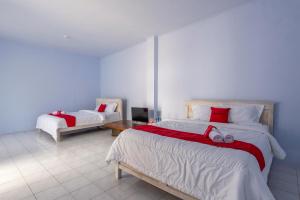 - une chambre avec 2 lits dotés de draps rouges et blancs dans l'établissement RedDoorz Syariah @ Bondowoso City Center, à Bondowoso