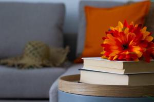 una pila de libros sobre una mesa con una flor encima en Sapore di Sori New Apartment, en Sori