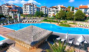 a large swimming pool with an umbrella and some buildings at Oasis Resort Lozenets in Lozenets