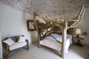 a bedroom with a canopy bed with tree branches and a chair at Masseria Quis Ut Deus in Crispiano