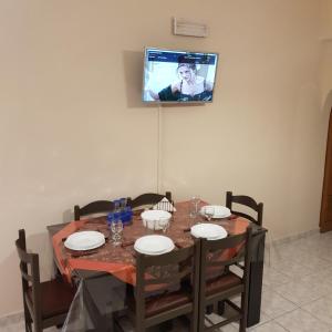 a dining room table with a tv on the wall at George's & Amalia's appartments 2 in Afantou