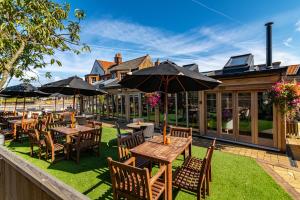 eine Terrasse mit Tischen, Stühlen und Sonnenschirmen in der Unterkunft The Lodge in Hunstanton