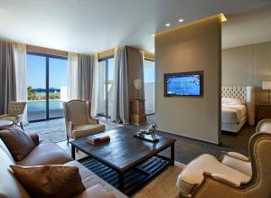 a living room with a couch and a tv on a wall at Pelagos Suites Hotel & Spa in Kos