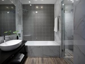 a bathroom with a tub and a sink and a shower at Pelagos Suites Hotel & Spa in Kos