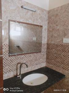 W łazience znajduje się umywalka i lustro. w obiekcie Sri Kamadhenu Residency w mieście Coimbatore