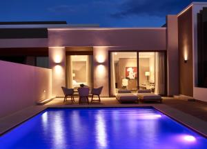 a villa with a swimming pool at night at Pelagos Suites Hotel & Spa in Kos