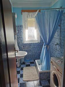 a blue tiled bathroom with a sink and a toilet at Gacka Rooms in Vrhovine