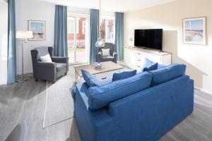 ein Wohnzimmer mit einem blauen Sofa und einem TV in der Unterkunft Deichsonne - mit Wintergarten und Blick Richtung Wattenmeer in Juist