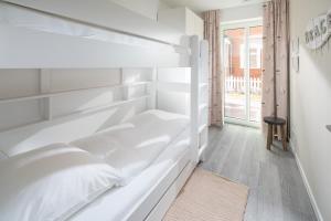 ein weißes Schlafzimmer mit einem Etagenbett und einem Fenster in der Unterkunft Deichsonne - mit Wintergarten und Blick Richtung Wattenmeer in Juist