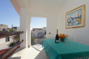 un tavolo con una bottiglia di vino e bicchieri sul balcone di Casa Marinella a Marinella di Selinunte
