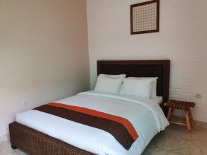 um quarto com uma cama grande e lençóis brancos em Naima Jiwo em Yogyakarta