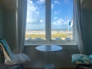 a table in front of a window with a view of the beach at Pacific, spectacular seaview in Bergen aan Zee