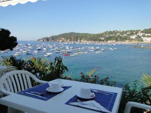 une table et des chaises blanches avec des bateaux dans l'eau dans l'établissement Hotel La Torre, à Calella de Palafrugell