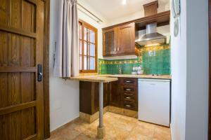 a kitchen with wooden cabinets and a white refrigerator at Hostal Don Joaquín Alora in Alora