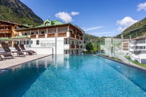 een zwembad voor een gebouw met bergen bij Alpenresidenz Ballunspitze - Kinderhotel in Galtür