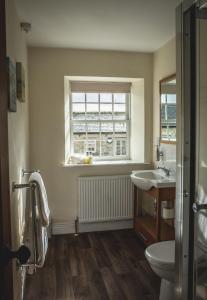 a bathroom with a sink and a toilet and a window at The Saddle Room in Middleham +103 photos