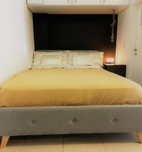 a bedroom with a bed with yellow sheets and a black headboard at Cozy Studio by seaside and tram in Athens