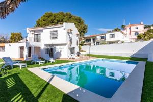 a villa with a swimming pool in front of a house at Villa Orquidea in Fuengirola
