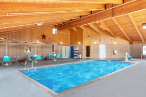 - une grande piscine dans un bâtiment avec des chaises bleues dans l'établissement AmericInn by Wyndham Calumet, à Calumet