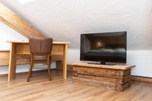einen TV auf einem Holztisch neben einem Stuhl in der Unterkunft Die Bruckmühle in Valley