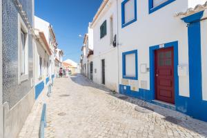 un vicolo con edifici blu e bianchi e una porta rossa di FLH Ericeira Cozy House with Terrace a Ericeira