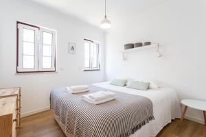 a white bedroom with a bed with two towels on it at FLH Ericeira Cozy House with Terrace in Ericeira