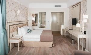 1 dormitorio con cama blanca, escritorio y TV en Rezone Health & Oxygen Hotel Kazdağları, en Altinoluk