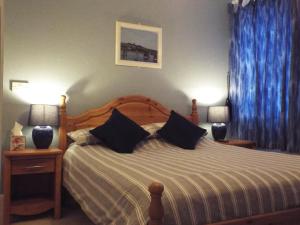 a bedroom with a large bed with blue curtains at Corner House Guest House in Bideford