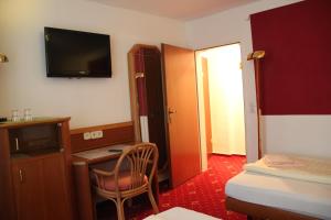 a hotel room with a desk and a television on the wall at Wali's Hotel in Bielefeld
