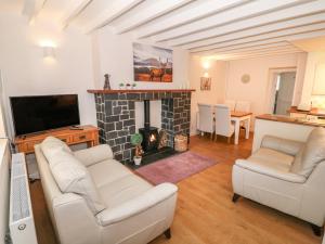 a living room with two white couches and a fireplace at Bwthyn Y Cwm in Betws-y-coed