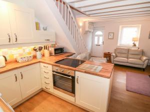 a kitchen with white cabinets and a staircase at Bwthyn Y Cwm in Betws-y-coed