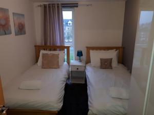 two twin beds in a room with a window at Howlands Bright 2 bed 2 bath apartment balcony with views over town in Crawley