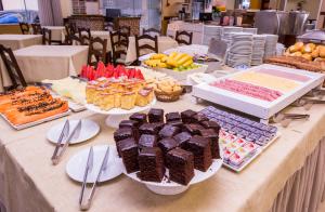 uma mesa com vários tipos diferentes de bolos e sobremesas em Hotel Itapema Meia Praia em Itapema