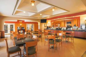 a restaurant with tables and chairs and a kitchen at La Quinta by Wyndham Islip - MacArthur Airport in Bohemia