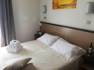 a bed with a white blanket and pillows on it at Hotel Royal in San Benedetto del Tronto