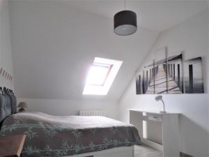 a white bedroom with a bed and a staircase at Orchidée in Berck-sur-Mer