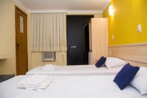 2 camas blancas en una habitación con paredes amarillas en Hotel Villa Rica en Río de Janeiro