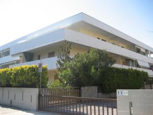 a white building with a fence in front of it at Condominio Piscina in Grado