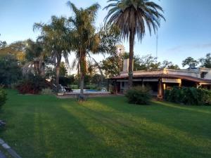 a house with palm trees in front of a yard at La Isolina Club de Campo in Villa María