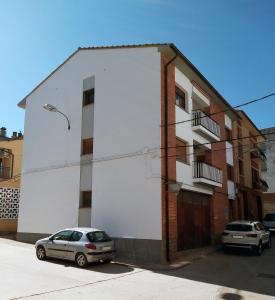 un edificio blanco con dos coches estacionados frente a él en CASA AGUILAR, en Castelserás
