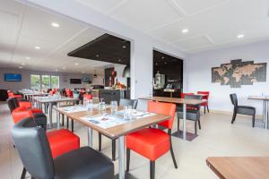 un restaurant avec des tables en bois et des chaises rouges dans l'établissement KYRIAD Issoudun, à Issoudun