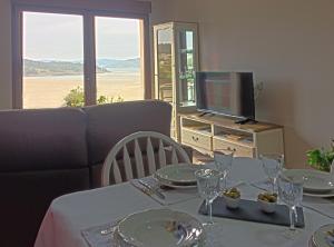 a dining table with plates and glasses and a television at Casa Mar de Fondo in A Telleira