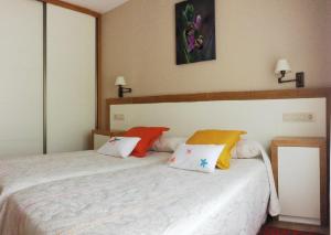 1 dormitorio con cama blanca y almohadas coloridas en Casa Mar de Fondo, en A Telleira