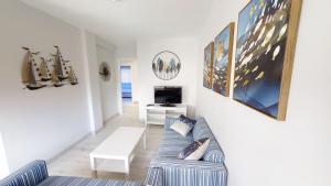 ein Wohnzimmer mit einem Sofa und einem TV in der Unterkunft Apartamentos Design Pinemar in Cabañas