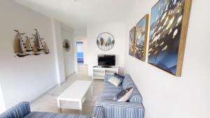 a living room with a couch and a tv at Apartamentos Design Pinemar in Cabañas